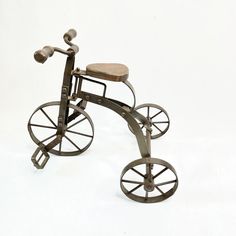 an old fashioned metal tricycle with wheels on it's back wheel and seat