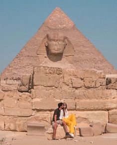 two people are sitting in front of the pyramids