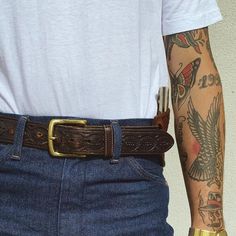 a man with tattoos on his arm wearing a belt