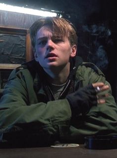 a young man sitting at a table with his hands folded