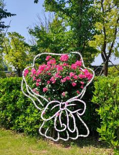 a garden sculpture with pink flowers in the shape of a bow on it's head