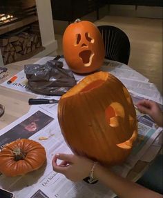 two pumpkins sitting on top of a table next to each other with faces carved into them