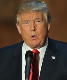 a close up of a person wearing a suit and tie with a microphone in front of him