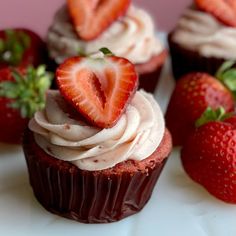 some cupcakes with strawberries on top of them