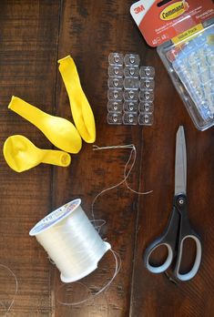 the supplies needed to make this craft include scissors, thread, and other items on a wooden table