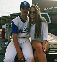 a man and woman sitting on the back of a truck