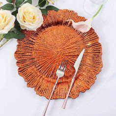 an orange plate with silverware and flowers on it