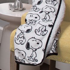 a white toilet sitting next to a bath tub covered in snoopy cartoon character blankets