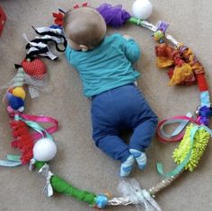 a baby is laying on the floor surrounded by toys and ribbons that are all around him