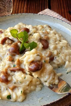 a white plate topped with macaroni and cheese covered in sausages next to a fork