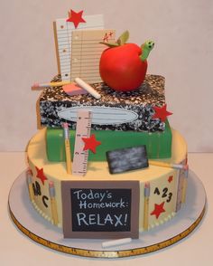 there is a cake made to look like an apple on top of books and pencils