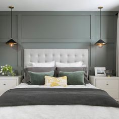 a bedroom with gray walls and white bedding, two lamps on either side of the bed