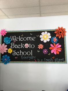 a welcome back to school sign hanging from the ceiling in an office building with flowers on it