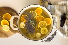 a pot filled with lemons and lavender on top of a wooden board next to a cutting board