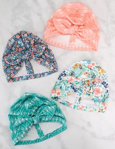 three baby hats are laid out on a marble surface