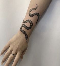 a woman's hand with a black snake tattoo on the left arm and wrist