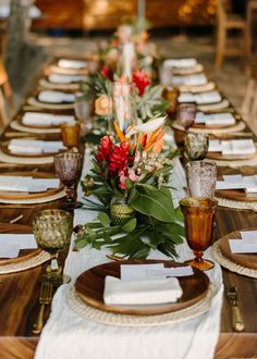 a long table set with place settings and flowers