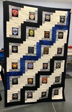 a large quilt with patches on it is being held up by someone's hand