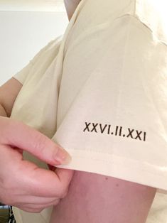 a man is holding his shirt with the word xxviii on it in black ink