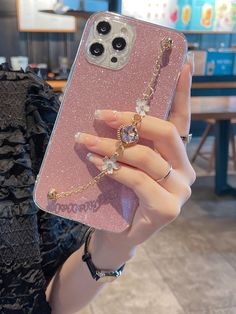 a person holding up a pink phone case with some jewels on the front and side