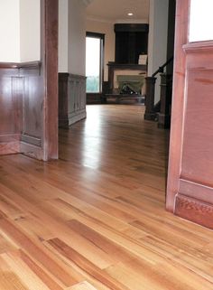 an empty living room with hard wood flooring and large open doorway to another room