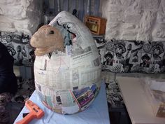 an inflatable animal sitting on top of a table next to a wall covered in newspaper