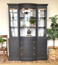 a black china cabinet with glass doors and gold handles in the middle of a room