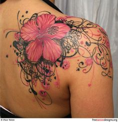 the back of a woman's shoulder with tattoos on it and flowers in the middle