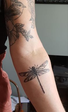 a woman's arm with a dragonfly tattoo on the left side of her arm