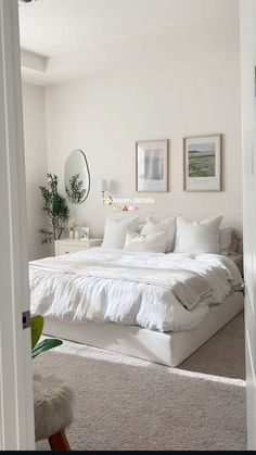 a white bed sitting in a bedroom next to a doorway with pictures on the wall