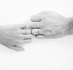 two people holding each other's hands with small tattoos on their thumbnails