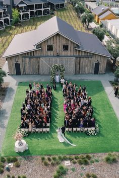 an aerial view of a wedding ceremony in front of a barn