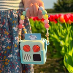 a person holding a small toy in their hand with flowers in the back ground and tulips in the background