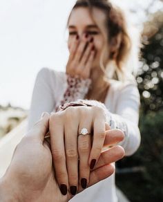 a woman holding the hand of a man who is covering his face with her hands