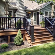 a wooden deck with black iron railings and hand rails in front of a house