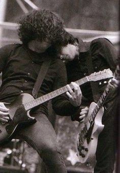 two men playing guitars on stage with one holding his head to the other's chest