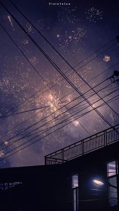 fireworks are lit up in the night sky above power lines and wires, as seen from an apartment building