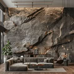 a living room with large rocks on the wall and wood flooring in front of it