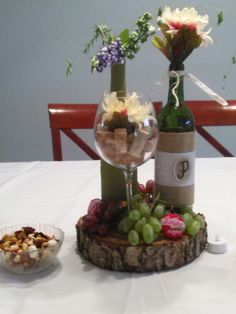 two wine bottles are sitting on a table with grapes and nuts