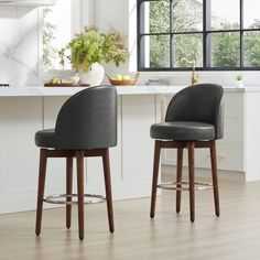 two gray bar stools sitting in front of a kitchen counter with potted plants on it