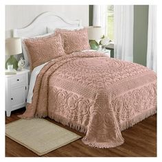 a bed with a pink bedspread and pillows