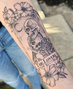 a person with a tattoo on their arm that has flowers and a skull in it