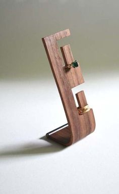 a wooden ring holder with two rings on it's sides and a green stone in the middle