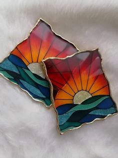 two stained glass plates sitting on top of a white surface