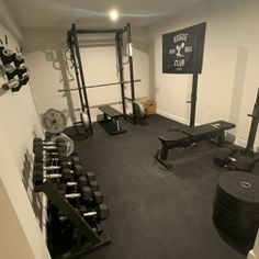 a home gym with black and white equipment in the corner, including dumbs, weight plates, and barbells