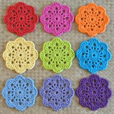 six crocheted coasters are arranged on a woven mat