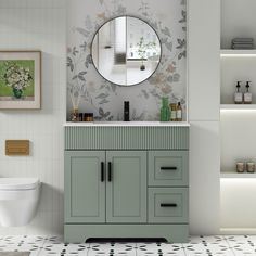 a white toilet sitting next to a bathroom sink under a round mirror on a wall