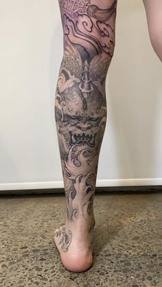 a person with tattoos on their legs and feet is standing in front of a wall