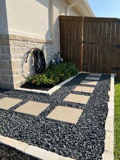 a small garden area with gravel, rocks and plants in the front yard next to a fence