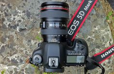 a close up of a camera on a rock with a red and black ribbon around it